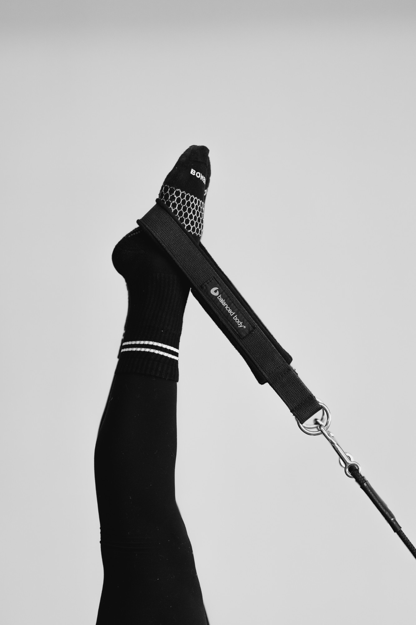 A leg extended upward in a Pilates foot strap